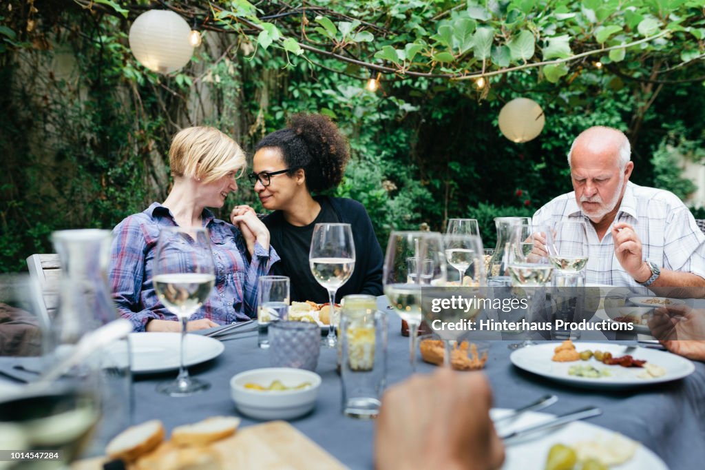 Lesbian Couple Holding Hands At BBQ With Family
