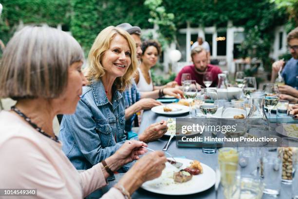 group of people enjoying an outdoor meal together - gemeinsam menschengruppe stock-fotos und bilder