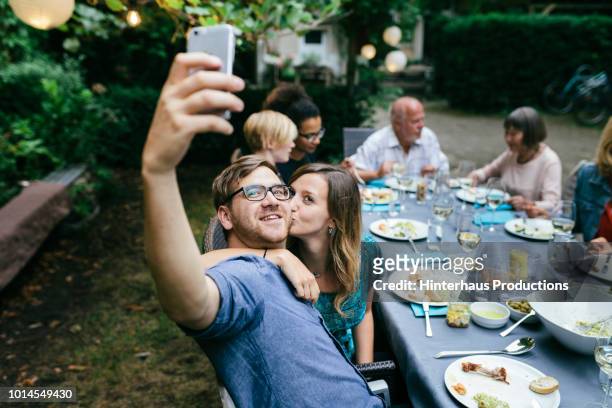 couple taking selfie during bbq with family - barbecue social gathering stock pictures, royalty-free photos & images