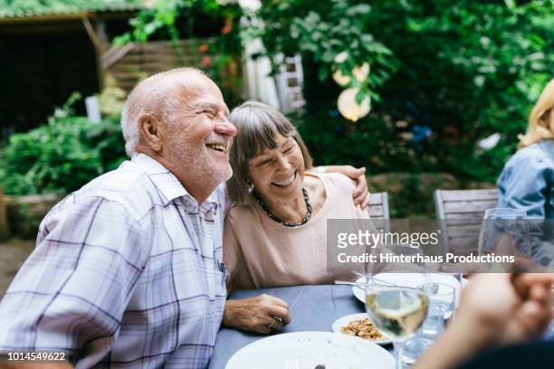 elderly couple enjoying outdoor meal with family - senior adult stock pictures, royalty-free photos & images