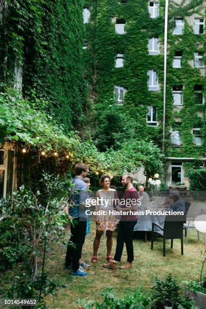 group of friends chatting after meal in courtyard - discussion germany outdoor friends stock-fotos und bilder