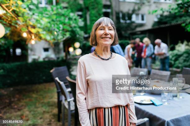 portrait of elderly woman smiling after bbq - rosa germanica foto e immagini stock