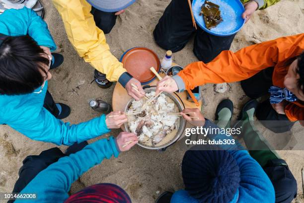 Directly above view of people eating lunch on a beach that was cooked over a fire