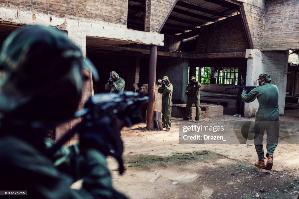 Amigos que juegan al Juego de guerra con armas de airsoft