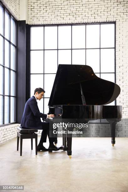 businessman playing piano - piano stockfoto's en -beelden