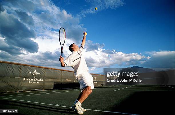 young man serving recreational tennis - sacada fotografías e imágenes de stock