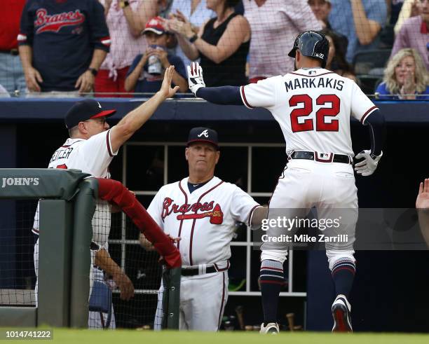 Right fielder Nick Markakis of the Atlanta Braves is congratulated in the dugout after scoring in the first inning during the game against the...