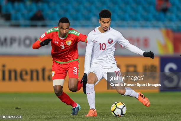Akram Afif of Qatar runs with the ball being defended by Majid Al Saadi of Oman during the AFC U23 Championship China 2018 Group A match between Oman...
