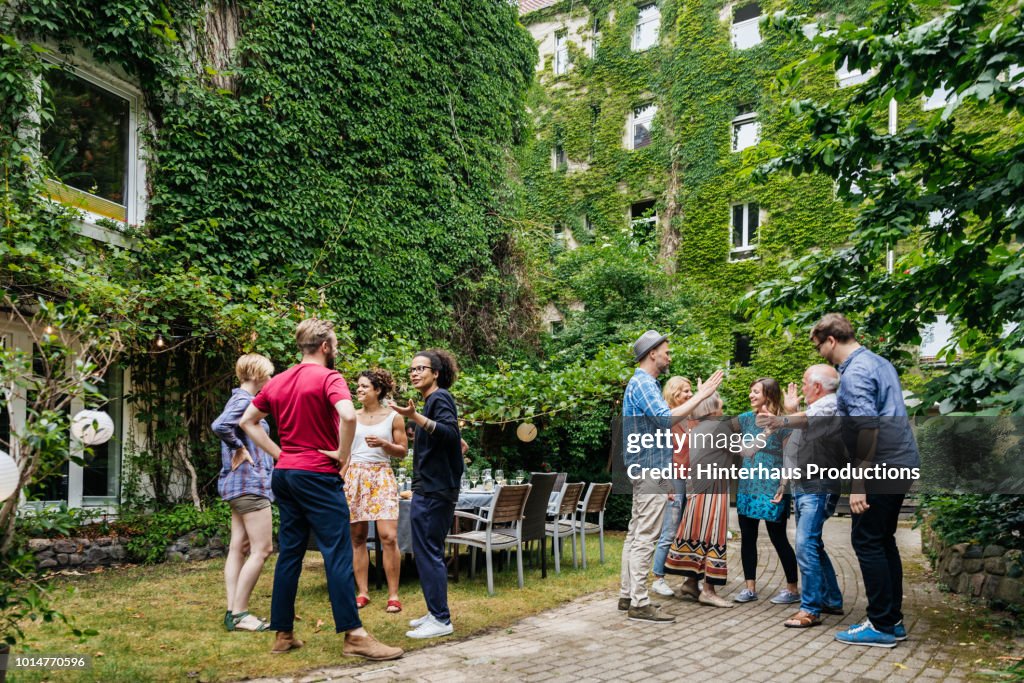 Group Of Family Members Greeting One Another Before Outdoor Meal
