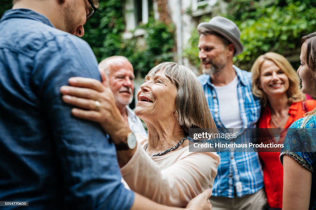 Elderly Lady Greeting Family Members In Courtyard