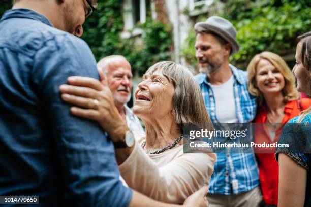 elderly lady greeting family members in courtyard - senior adult stock-fotos und bilder