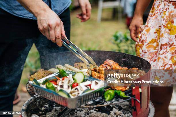 close up of man cooking food on bbq - barbecue stockfoto's en -beelden