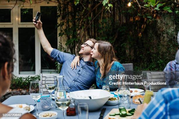 couple taking selfie at bbq with family - long table stock pictures, royalty-free photos & images