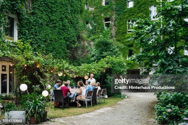family enjoying an outdoor meal together - food table stock-fotos und bilder
