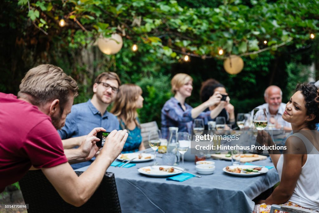 Man Taking Photo Of Friends At Family BBQ