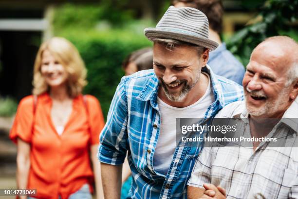 man laughing with father during family bbq - sólo con adultos fotografías e imágenes de stock