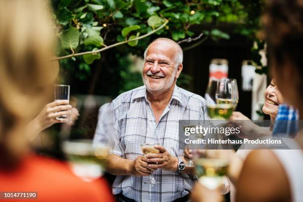 elderly man making toast at family bbq - wijn tuin stockfoto's en -beelden