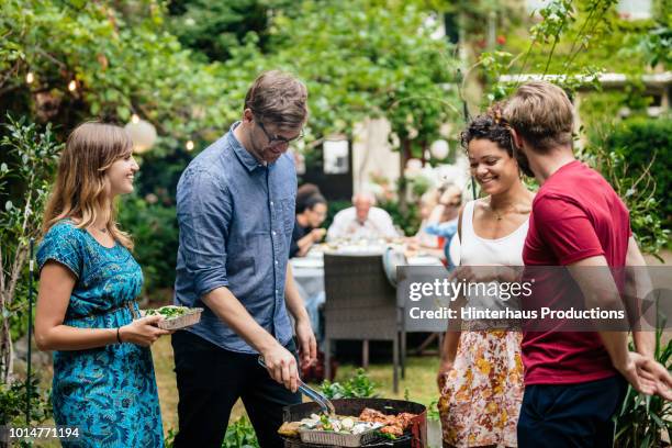 friends cooking together at bbq with family - garden barbecue stockfoto's en -beelden