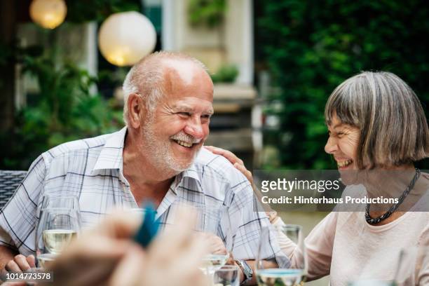 elderly couple smiling at family bbq - senior couple stock pictures, royalty-free photos & images