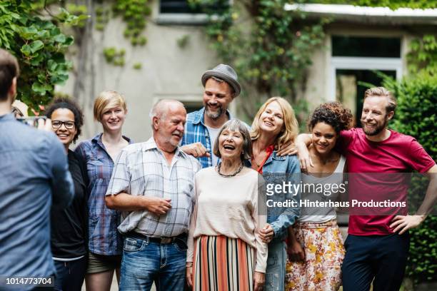 man taking group photo of family at bbq - mixed race family photos et images de collection