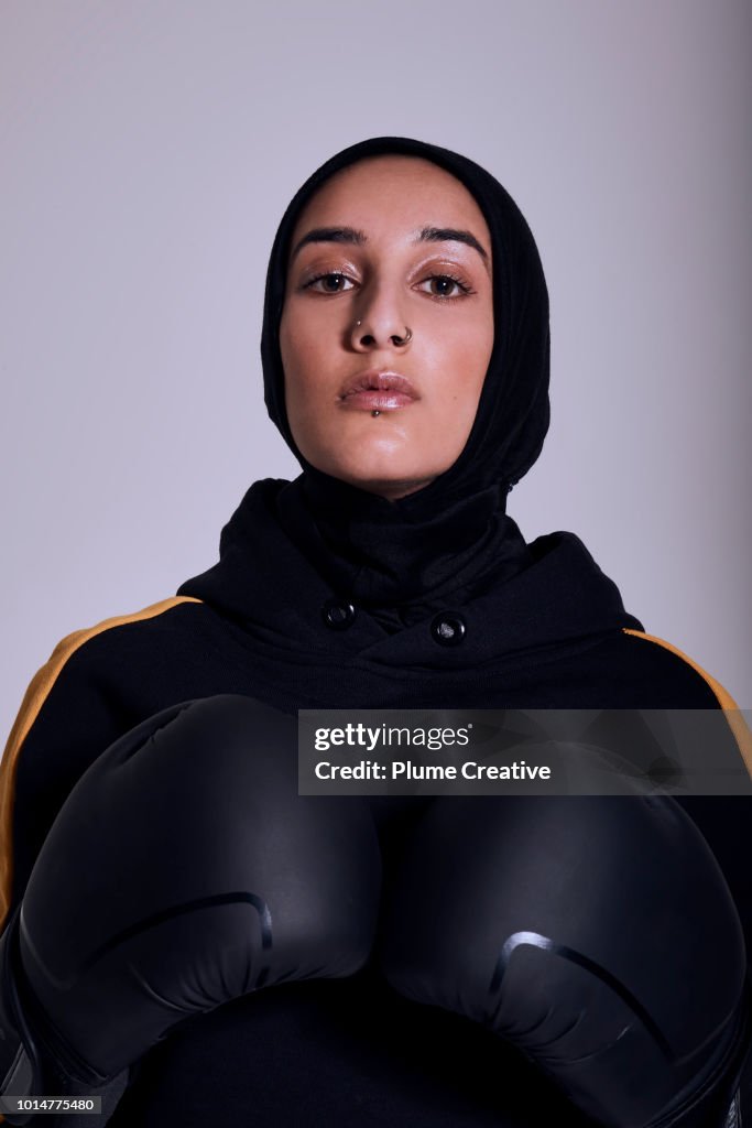 Confident Muslim woman poses with boxing gloves