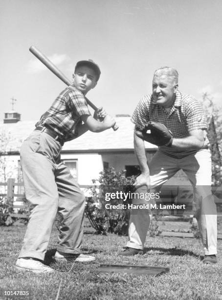 Father And Son Playing Baseball In Backyard