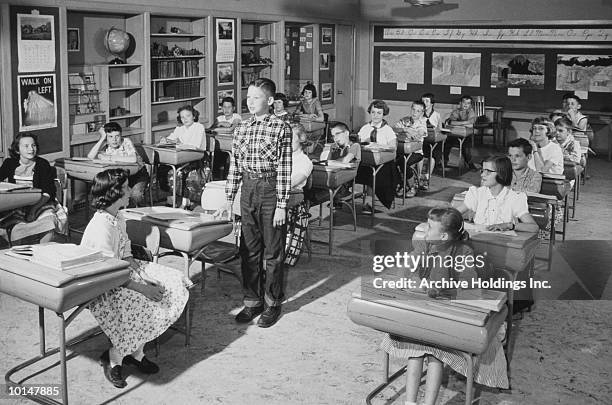 boy stands beside desk in classroom - school classe picture stock-fotos und bilder