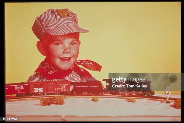 YOUNG BOY IN ENGINEER OUTFIT WITH TOY TRAINS