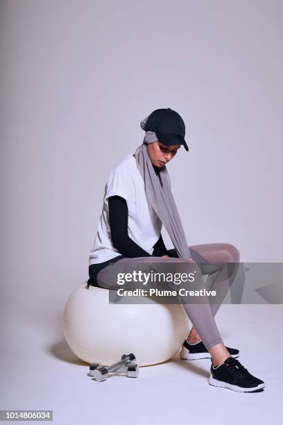 woman on fitness ball with hand weights - woman scarf trousers stock-fotos und bilder