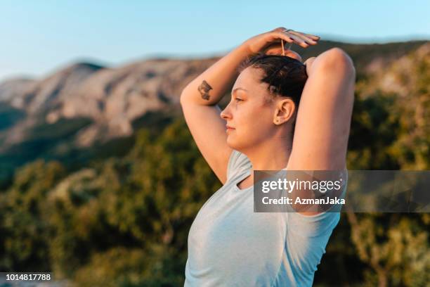 woman with diabetes wearing a cgm and making a ponytail - diabetes lifestyle stock pictures, royalty-free photos & images