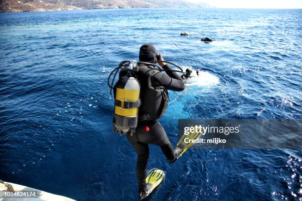 divers jumping from the boat in water - dove imagens e fotografias de stock