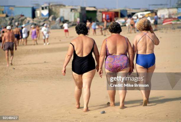 middle aged women walking on beach, spain - traje de baño de una pieza fotografías e imágenes de stock