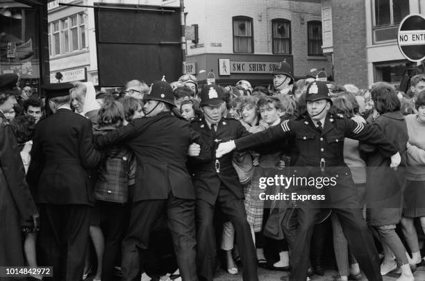 Police holding back crowds of teenagers in a queue for tickets to a Beatles concert, on the corner of Halford Street and Charles Street, Leicester,...