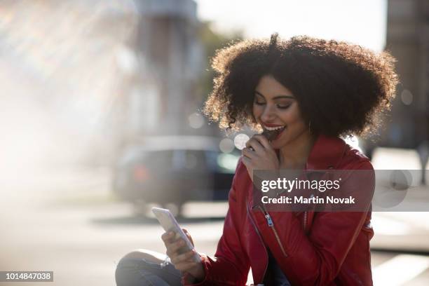 always connected - teen girl on phone in street - chocolate eating ストックフォトと画像