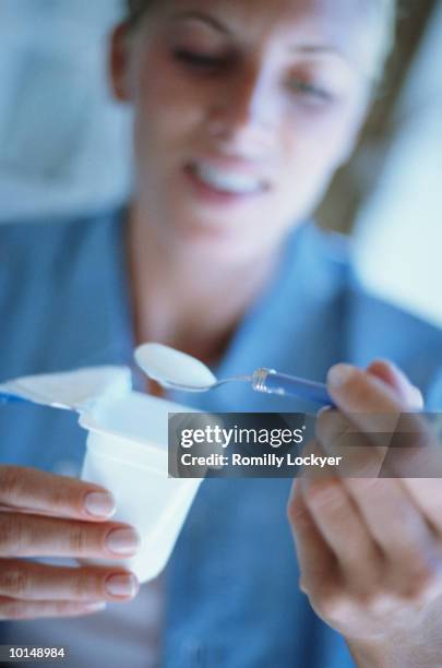 young woman eating yogurt - joghurtbecher stock-fotos und bilder