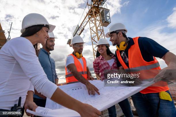 group of civil engineers looking at a blueprint at a construction site - civil engineer stock pictures, royalty-free photos & images