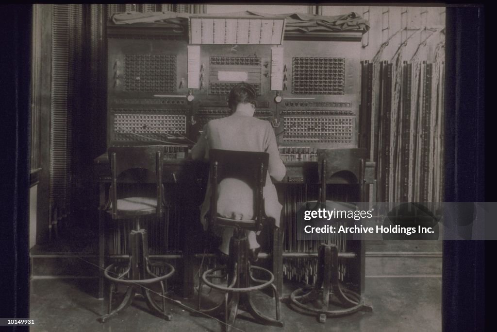 WOMAN OPERATES A LARGE SWITCHBOARD