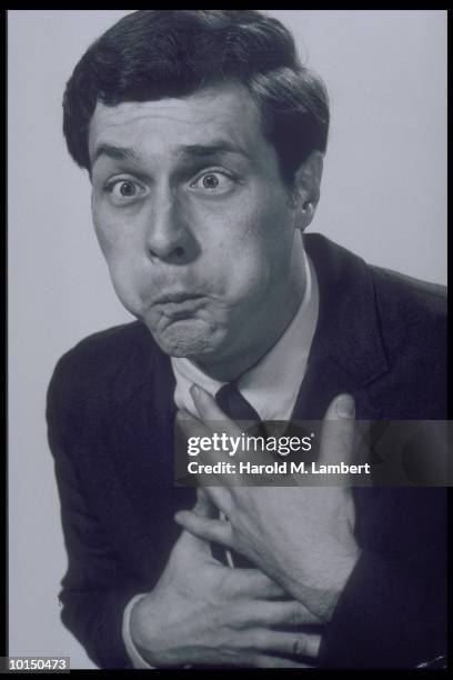 MAN HOLDING CHEST & PUFFING CHEEKS, CIRCA 1960