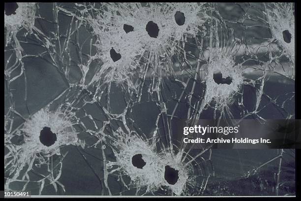 dozen bullet holes riddle pane of glass - bullet hole stock pictures, royalty-free photos & images