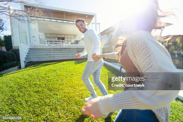 excited couple running into their new luxury home. - lawn mover stock pictures, royalty-free photos & images