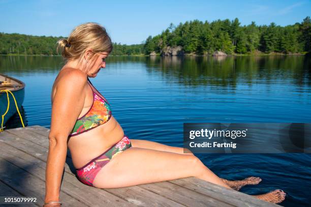 a mature woman wearing a bikini on vacation concerned about her weight. - chubby swimsuit stock pictures, royalty-free photos & images