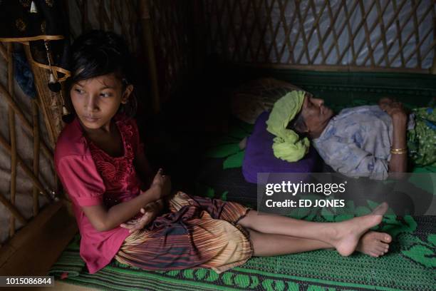 Rohingya refugee Saida Bibi sits before her relative Bodu Zzaman , at the Kutupalong refugee camp near Cox's Bazar on August 11, 2018. - According to...