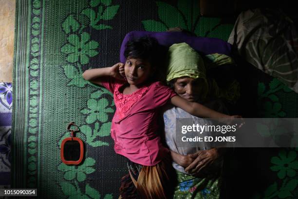 Rohingya refugee Saida Bibi, 8 lies beside her relative Bodu Zzaman at the Kutupalong refugee camp near Cox's Bazar on August 11, 2018. - Bibi, who...