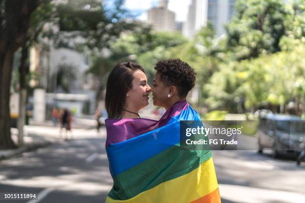 lesbisches paar mit regenbogenfahne - gay kiss stock-fotos und bilder