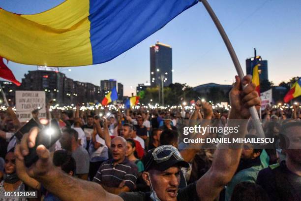 People wave Romanian national flags as they chant slogans during a demonstration to protest against the government on August 11 in Bucharest. -...