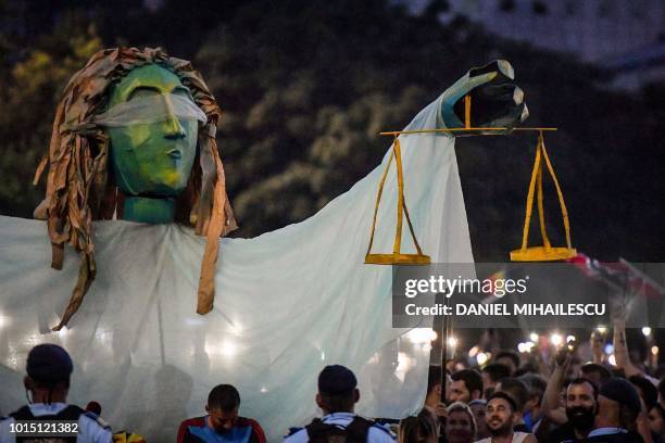 People chant slogans as they stand next to a giant statue picturing the symbol of justice during a demonstration to protest against the government on...