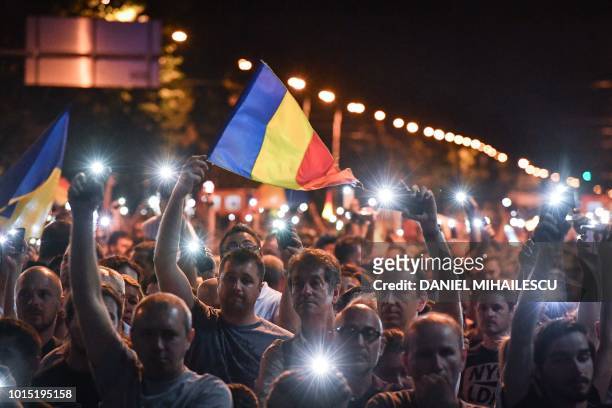 People wave Romanian national flags during a demonstration to protest against the government on August 11 in Bucharest. - Romania' s capital...