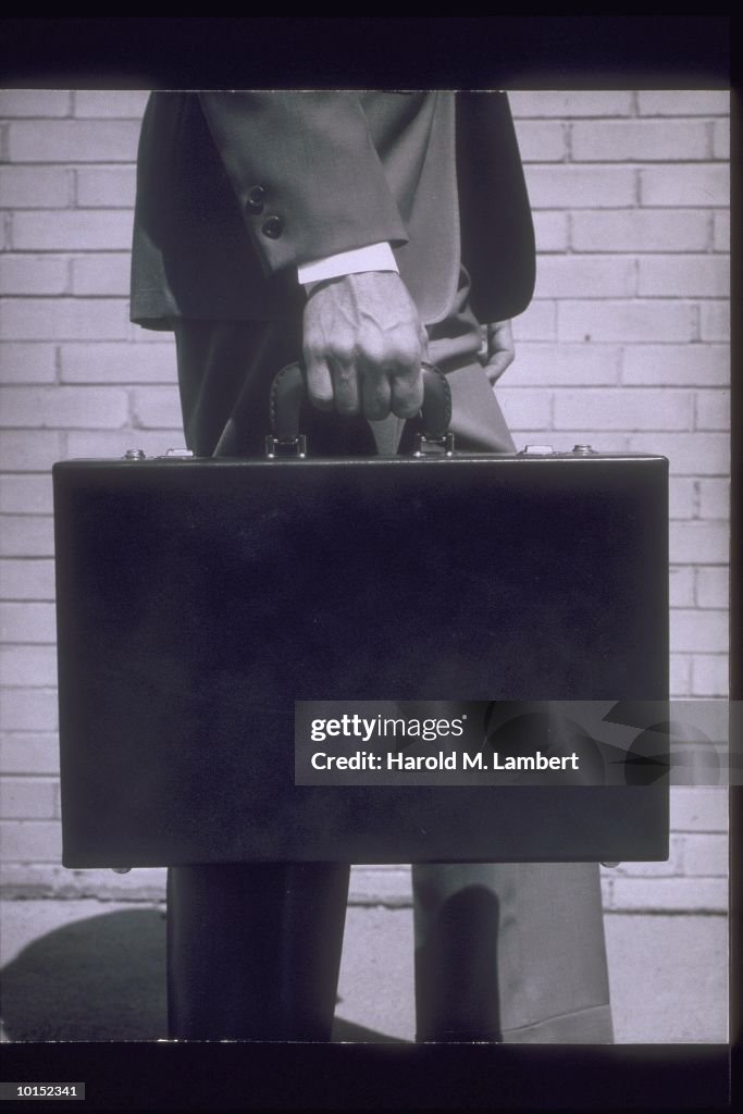 MAN HOLDING BRIEFCASE AT SIDE, CIRCA 1950S