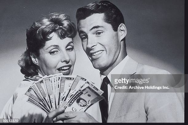 couple smiling at a spread of money - geld stock-fotos und bilder