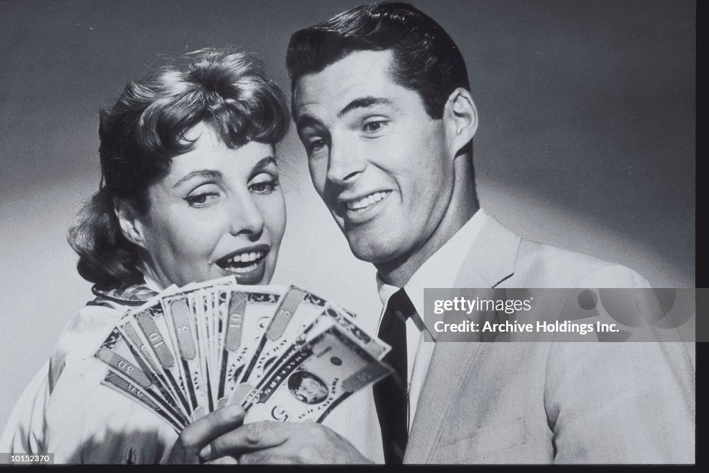 COUPLE SMILING AT A SPREAD OF MONEY